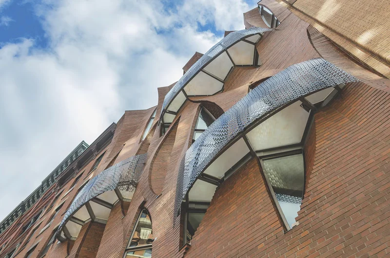 Looking up the same brick facade to leaf-shaped skylights set into the folded masonry.